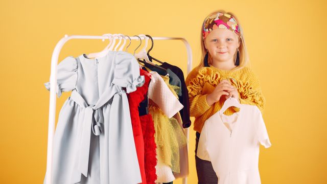 Cute little girl with shopping bags on a yellow background
